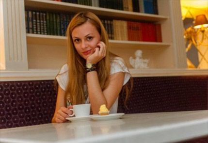Woman enjoying coffee at a cozy cafe table with books behind