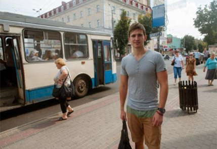 Man standing on a city street sidewalk near a trolley bus stop in daytime