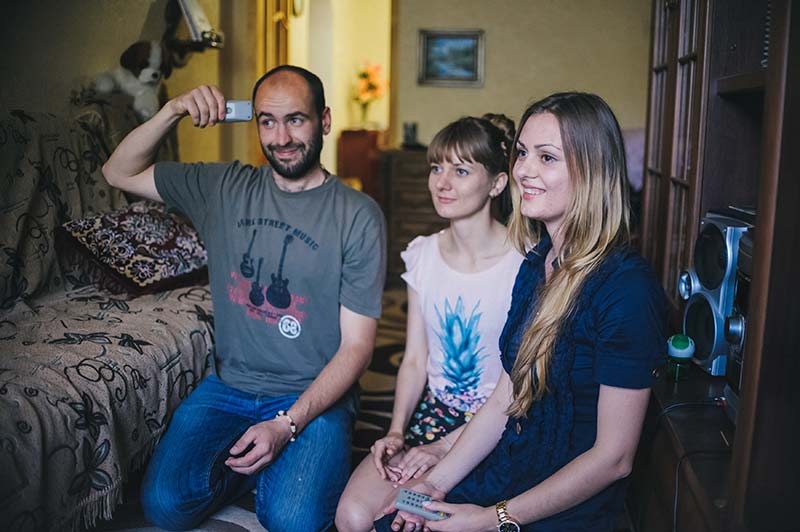 A group of three young people watching TV.