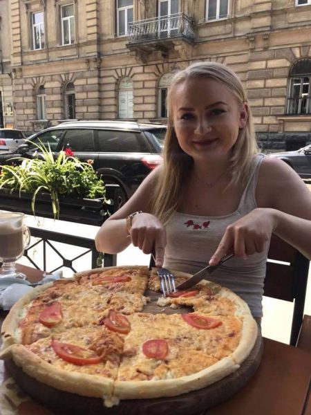 12-3M-3-pizza A young woman eating a pizza on a patio